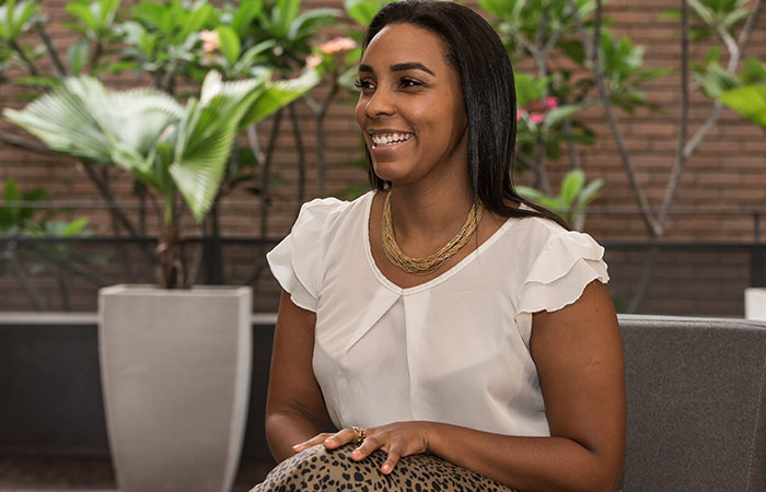 Retrato de Patrícia Soares sorrindo, usando uma blusa branca e colar bege